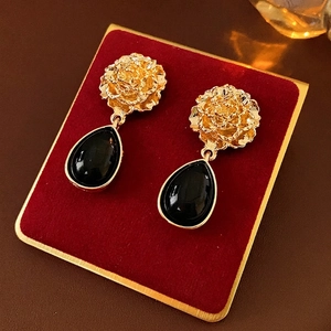 Vintage gold flower earrings with black water drop pendants on red velvet display
