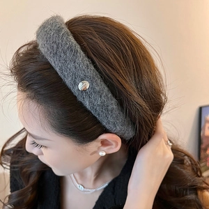 Detail of grey wool knit headband with a silver metal button on dark hair woman