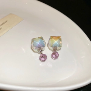 Detailed macro of aurora cube earrings with pink crystal drop on white ceramic plate