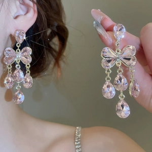 Gros plan de boucles d'oreilles nœud en cristal rose avec pampilles en gouttes d'eau