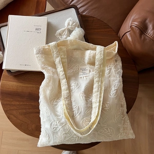 Close-up of vintage beige lace floral embroidery on lightweight cotton tote bag detail