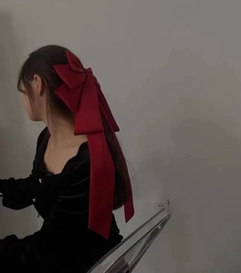 Elegant red oversized ribbon bow hair clip in satin finish on female model back view
