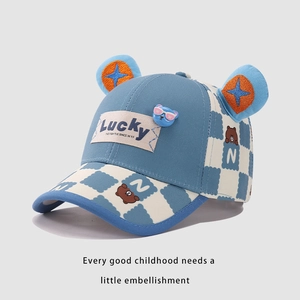 Detail of blue checkerboard kids baseball cap featuring 3D ears and Lucky bear patch