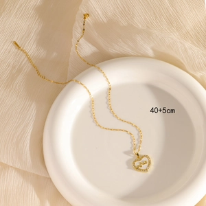 Gold heart pendant necklace with zircon and shell inlay on a ceramic plate