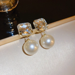 Macro view of gold stud earrings with square cubic zirconia and large white pearls