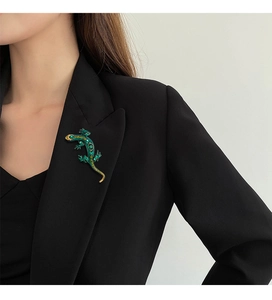 Detail of green lizard brooch with gold-tone plating and sparkling rhinestones on model