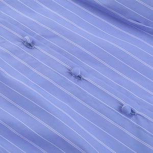 Dettaglio macro del tessuto a righe blu con bottoni rivestiti e cuciture rifinite con cura