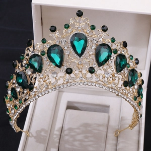 Detailed close-up of golden Baroque tiara with emerald crystals in a beige display box