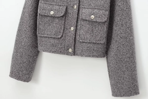 Detail showing grey tweed fabric texture and embossed silver metal buttons on a jacket