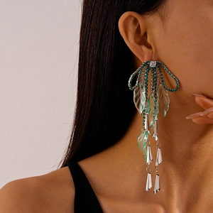 Detail of long tassel earrings featuring green rhinestones, bows and resin leaf pendants