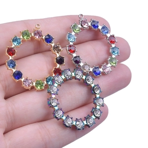 Detail of round rhinestone pendants in gold, silver and rainbow plating on a hand