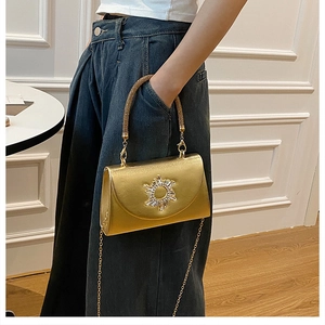 Detail of gold evening bag featuring rhinestone sun motif and elegant chain strap