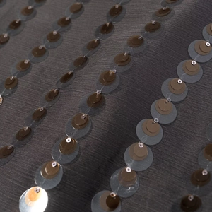 Macro shot of charcoal grey jumpsuit fabric with bronze sequins in vertical stripes