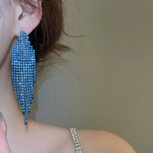Gros plan d'un mannequin portant de longues boucles d'oreilles pompon en strass bleu