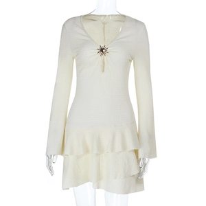 Détail de la robe blanche avec boucle soleil dorée et découpes au col en V profond