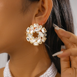 Close-up of elegant gold wreath earrings with clear crystals on a female model