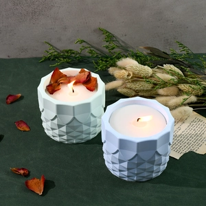 Close-up of geometric embossed scented candles in pearl white and light blue glass jars