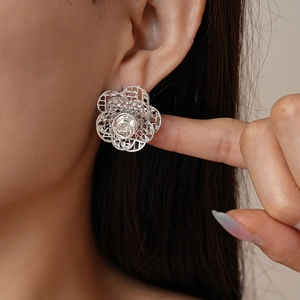 Nahaufnahme eines Models mit minimalistischen silbernen Hohlblütenohrringen aus Metalldraht