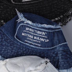 Dettaglio ravvicinato del cappello bucket in denim con bordi a frange e ricami