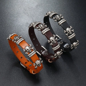 Detailed view of three multilayer leather bracelets with metal skull charms in varied colors
