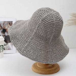 Handcrafted grey wide-brim crochet sun hat displayed on a wooden stand in a lifestyle scene