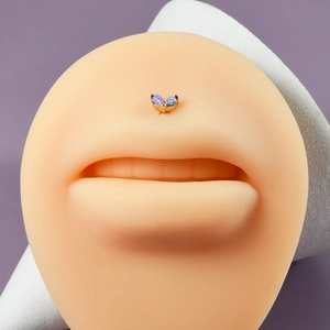 Detail of gold labret stud with iridescent opals on a silicone lip model