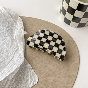 Detail of checkered hair claw clip in black and white on elegant leather surface