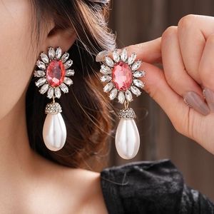 Gros plan de boucles d'oreilles avec pierres roses et pendentifs perles blanches