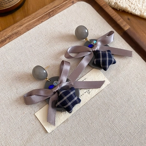 Détail de boucles d'oreilles nœud en tissu et pendentif étoile à carreaux bleus
