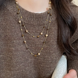 Close-up of vintage tiger eye double-layered necklace on a knit sweater backdrop