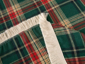 Detail of red and green plaid tablecloth with soft beige tassels and fabric texture