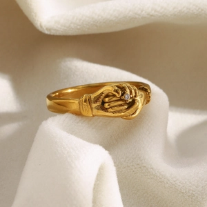 Vue détaillée de la bague poignée de main dorée avec zircon sur un tissu en velours