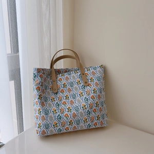 Détail d'un sac cabas en coton fleuri vintage avec poignées en cuir et rivets