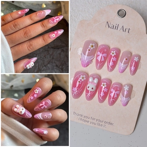 Detail of pink gradient almond nails with 3D bunny, bow, and white floral accents