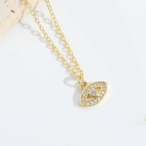 Detailed view of gold Evil Eye necklace featuring micro-pave cubic zirconia on a warm background