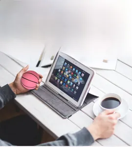 Pink hollow stress ball with basketball texture held by hand in office setting