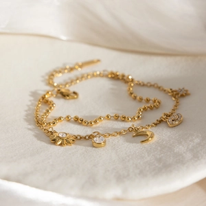 Détail du bracelet double couche doré avec breloques lune étoile et œil sur plateau