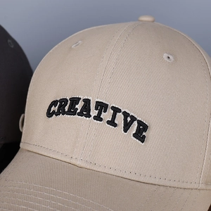 Macro shot of 3D embroidered CREATIVE letters on khaki cotton twill baseball cap