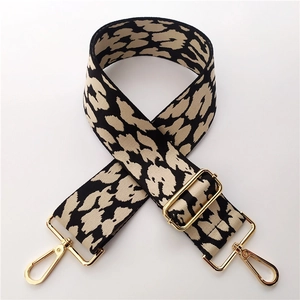 Detailed view of wide leopard print bag strap with golden lobster clasps and metal buckle