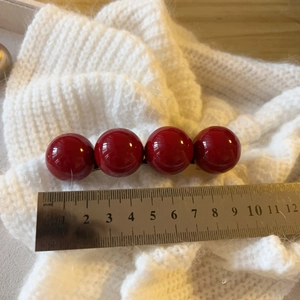 Detail showing 8cm high-gloss deep red bead hair clip on white knit background