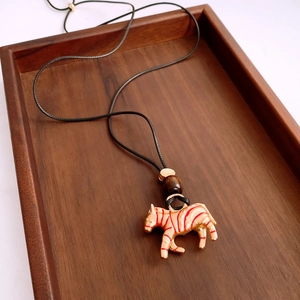 Detail of creative gold zebra pendant with red stripes and dark wooden bead on black cord