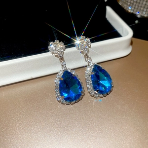Macro detail of pear-shaped blue sapphire earrings with shimmering halo micro-pave setting