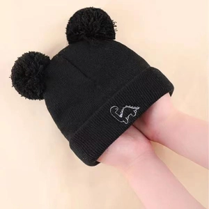 Kids black knit beanie featuring plush double pom-poms and cute dinosaur embroidery