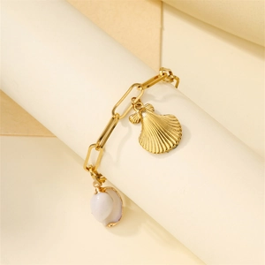 Detailed close-up of golden stainless steel bracelet with shell and conch charms