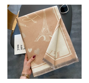Detail of beige cashmere-feel scarf featuring Eiffel Tower patterns and fringe edges