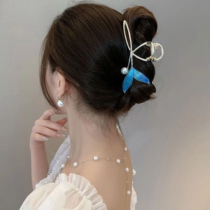 Detail of blue fish tail hair claw with pearls worn on a bun hairstyle for women