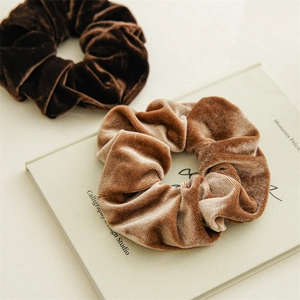 Dettaglio di elastici scrunchie giganti in velluto nei colori caffè e cammello