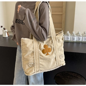 Detail of beige canvas tote bag with fringed edges and brown floral patch accent