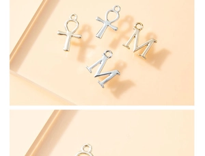 Macro detail of silver Ankh cross and letter M charms for DIY jewelry making