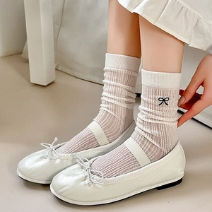 Beige hollow mesh slouch socks featuring black bow accents and Mary Jane shoes